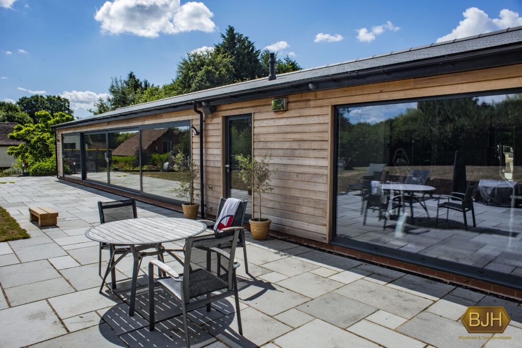 black aluminium sliding doors next to a stone patio with a blue sky