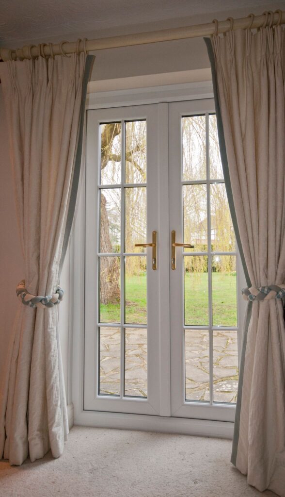 uPVC French doors with astragal bars framed by cream curtains