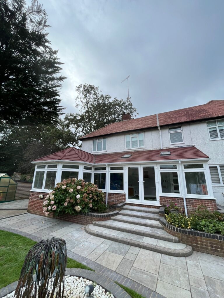 home conservatory made out brick windows and glass doors with white frames. on the roof of the conservatory there are two small windows