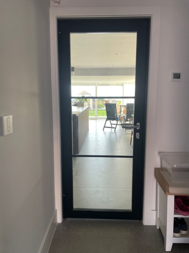 glass door with a black frame that has been recently installed inside someones home